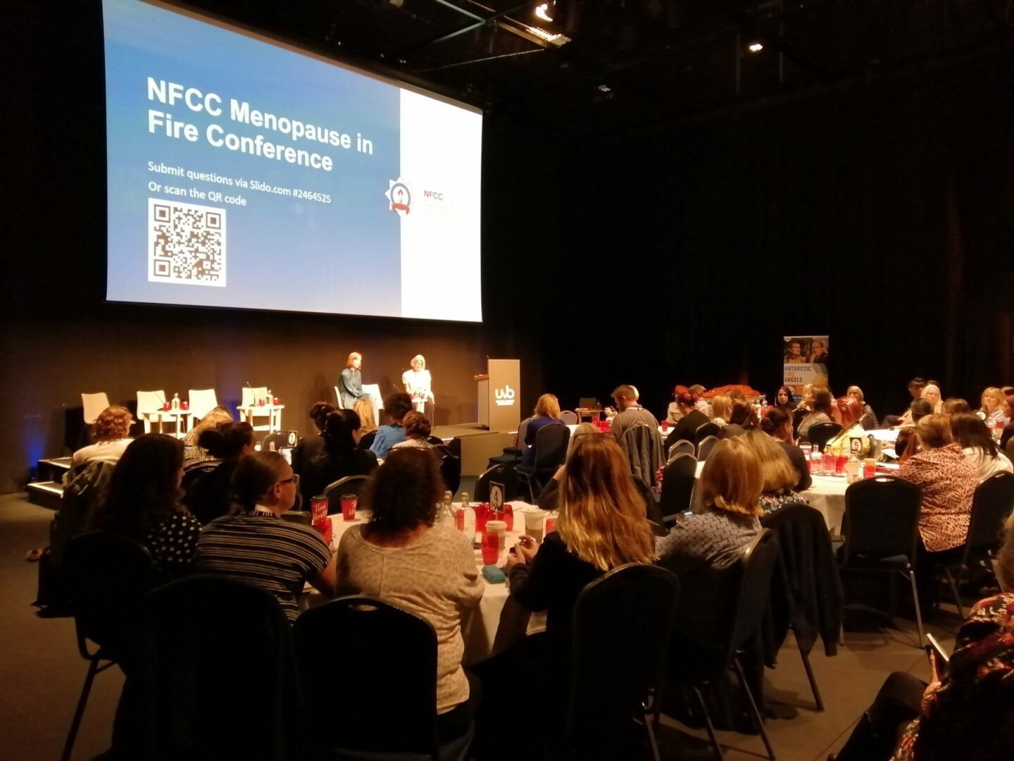 This image shows a room full of people, sitting in front of a large projector screen.